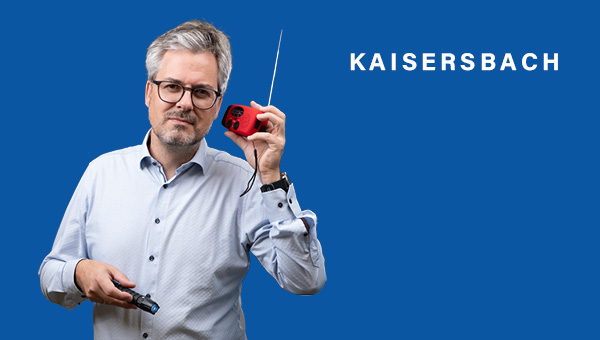 Michael Clauss hält sich ein rotes Kurbelradio ans Ohr