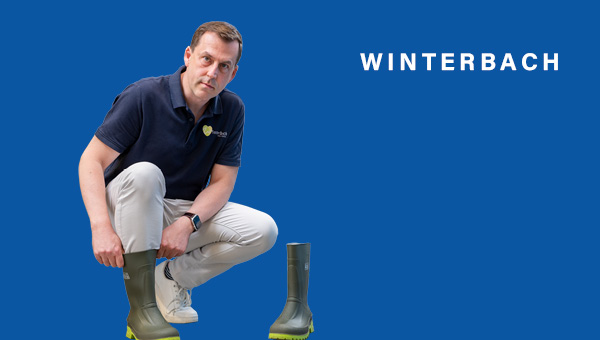 Sven Müller zieht sich kniend Gummistiefel an, er schaut in die Kamera