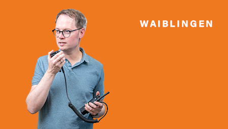 Sebastian Wolf mit einem Funkgerät, er lacht in die Kamera